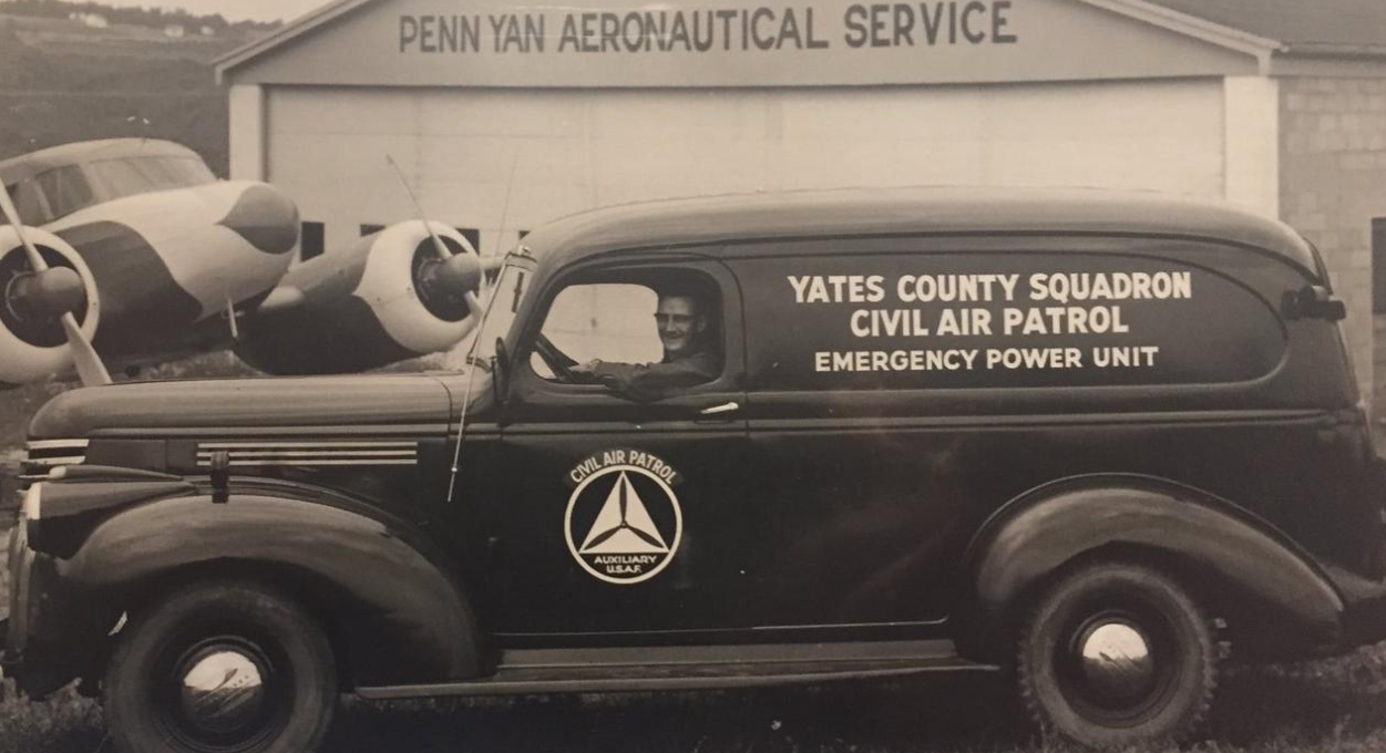 Historical Penn Yan Aeronautical Service hangar with a Civil Air Patrol vehicle and twin-engine aircraft